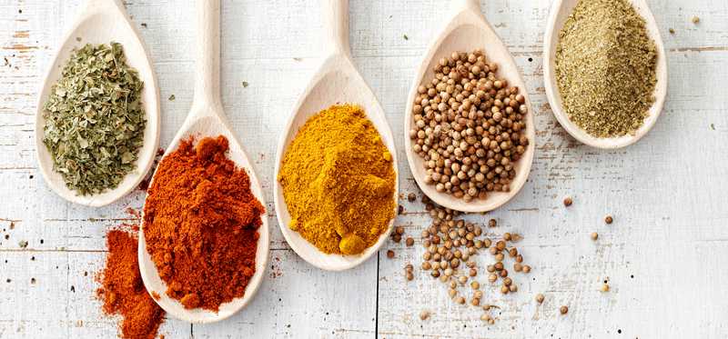 Spoons filled with different colorful spices.