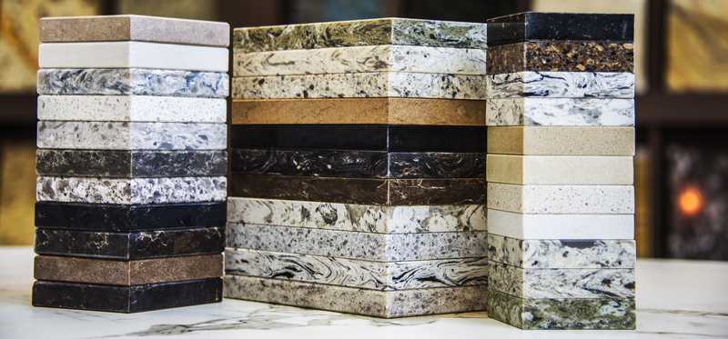 Stacks of kitchen countertop samples in granite, marble, and quartz.