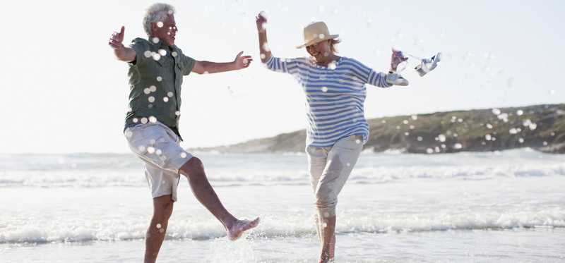 Elderly couple splashing through the water on a beach shoreline