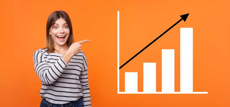 A happy person with a big smile on their face standing next to chart showing stock growth.