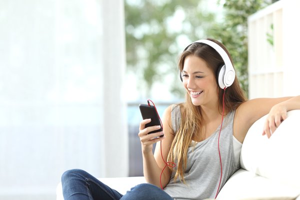 A woman listening to music with headphones through her smartphone.