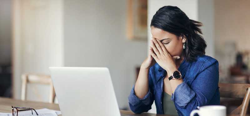 Person looking stressed while using a laptop.