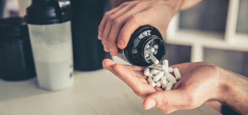 Supplements are being poured out of a jar.