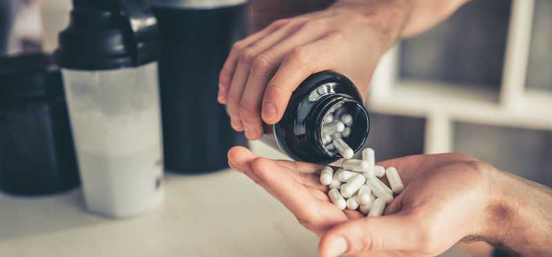 Supplements are being poured out of a jar.