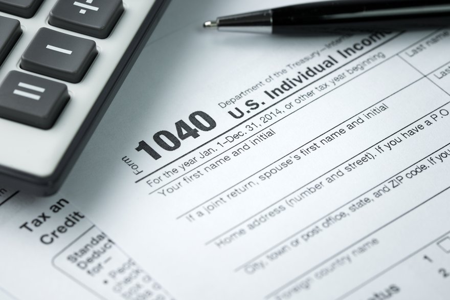 IRS form 1040 with a calculator and pen resting on top.