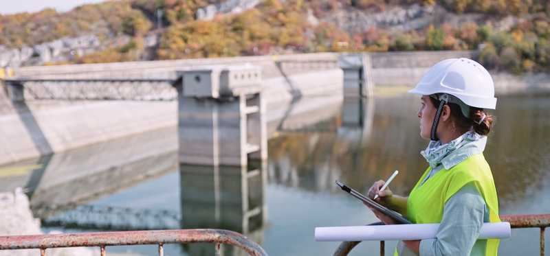 Technician and a large dam at a water reservoir.