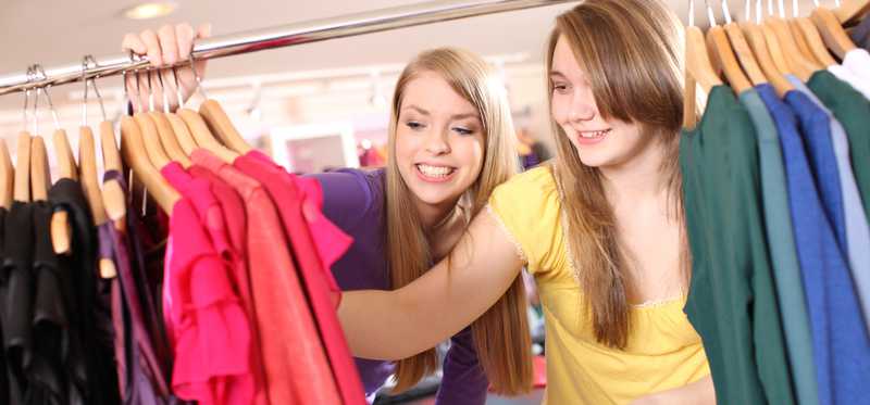 Two young women shop for clothes.
