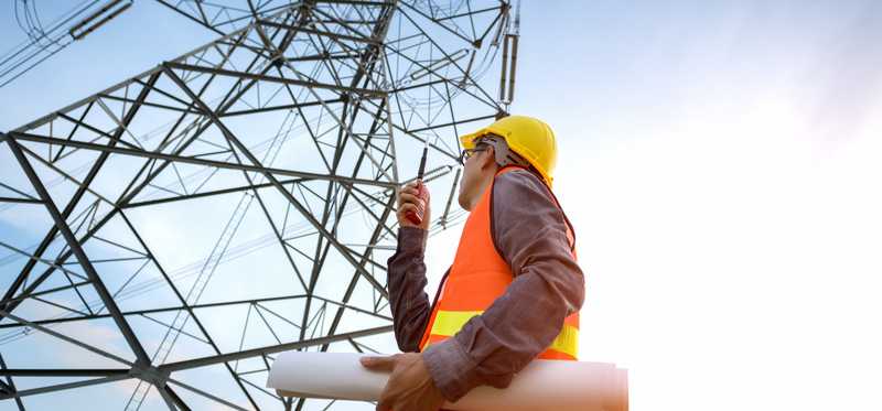 A worker standing at the bottom of a telecom tower.