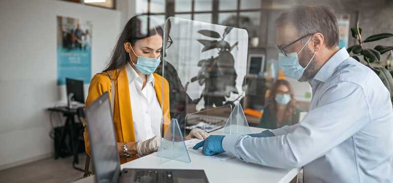 Two masked people at a bank counter.