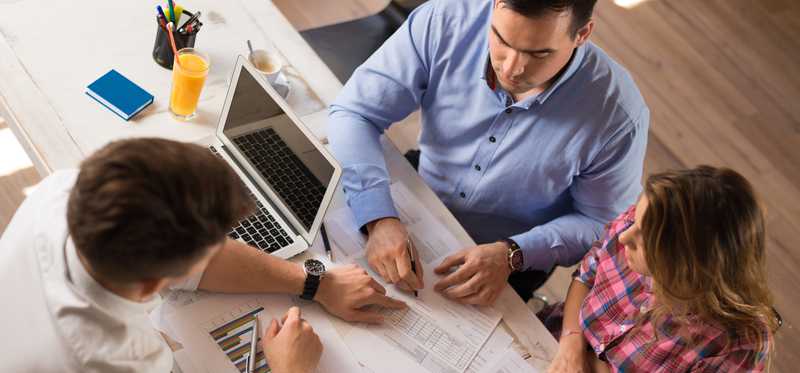 Three people at a table looking at papers and planning.