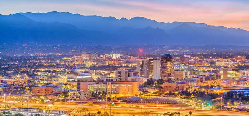 The Tucson, Arizona, skyline with mountains in the background at dusk.