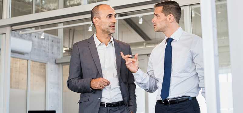 Two people in suits conversing.