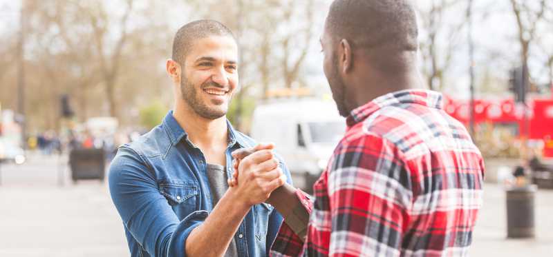 Two men shake hands outdoors.