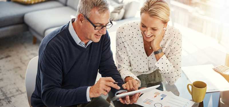 Two people working on a tablet and paperwork.