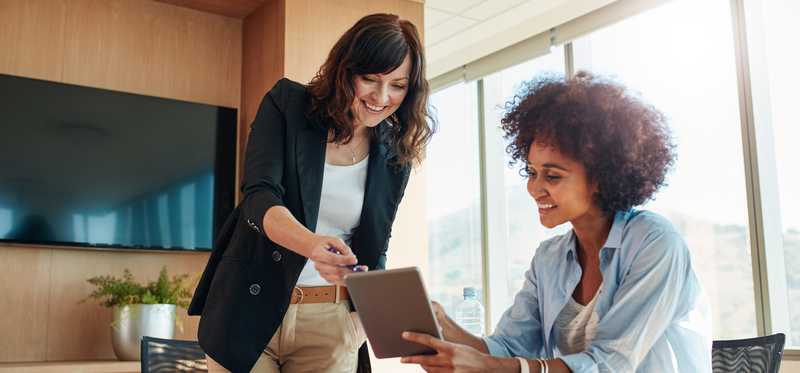Two professional females looking at a tablet.