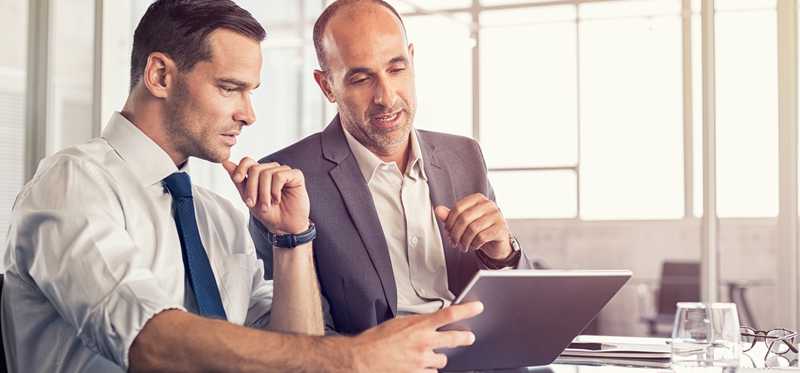 Two professional men looking at a tablet.