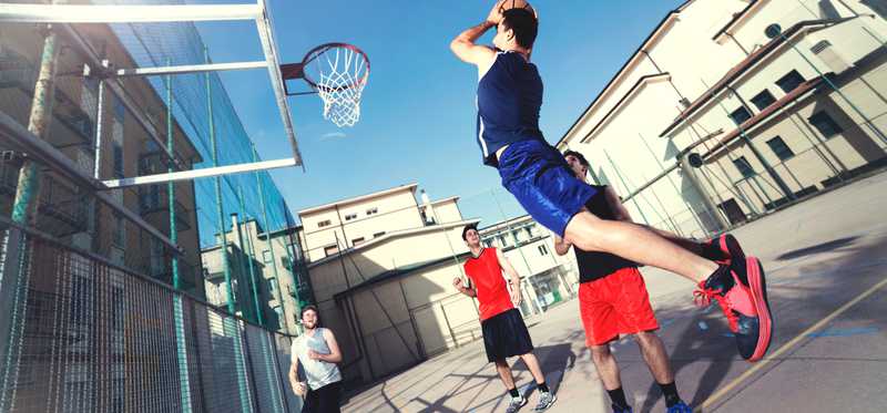 Young men play basketball.