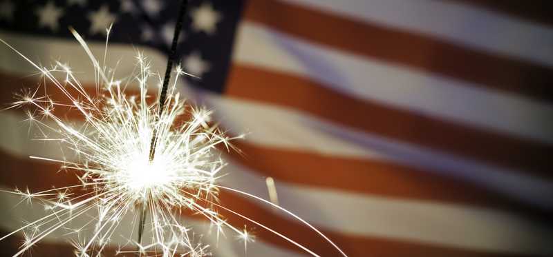 US flag with sparkler in front of it.