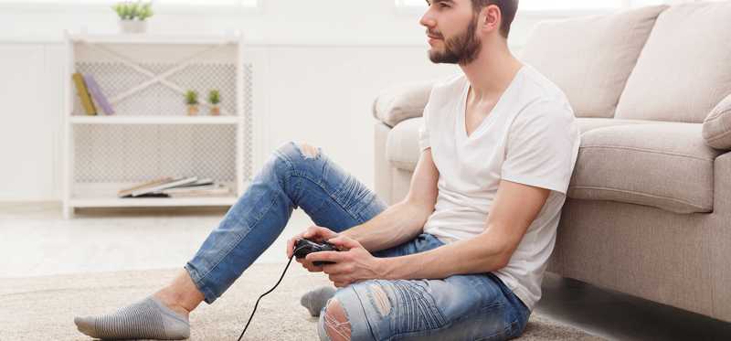 Man sitting on floor holding video game controller