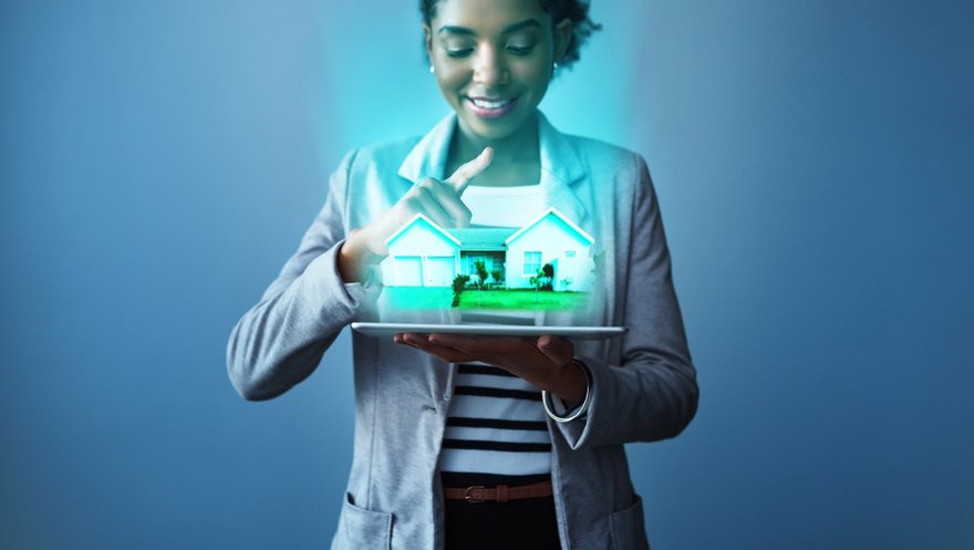 A person looks at a virtual house hovering above a tablet.