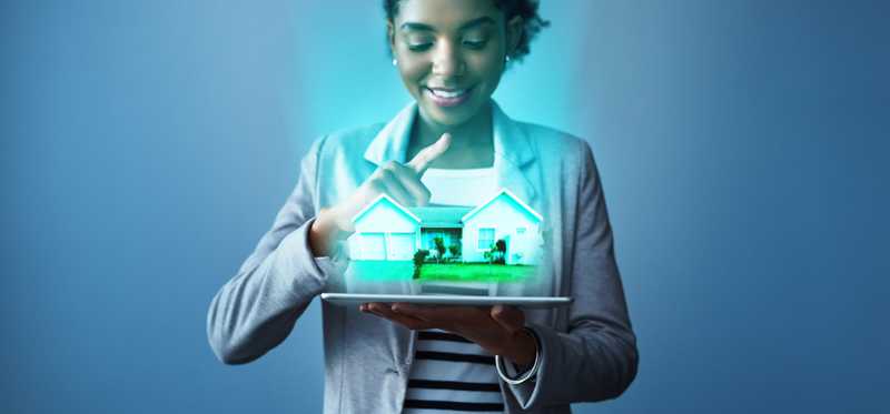 A person looks at a virtual house hovering above a tablet.