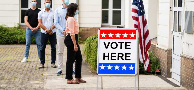 Voters waiting in line by Vote Here sign