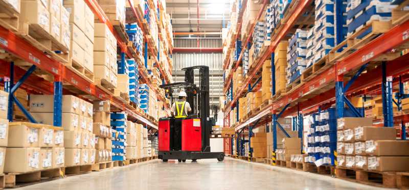 Warehouse worker driving a forklift in big-box store.
