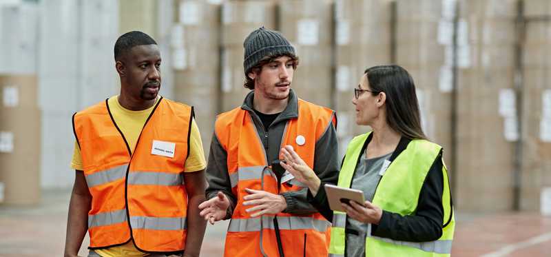 Three people talking inside a warehouse.