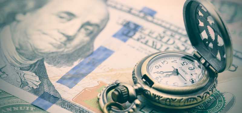 A stopwatch on a hundred dollar bill.