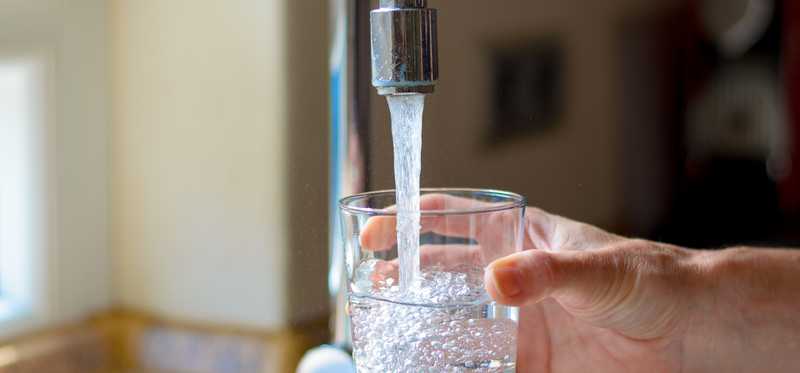Water is poured into a glass from a tap.