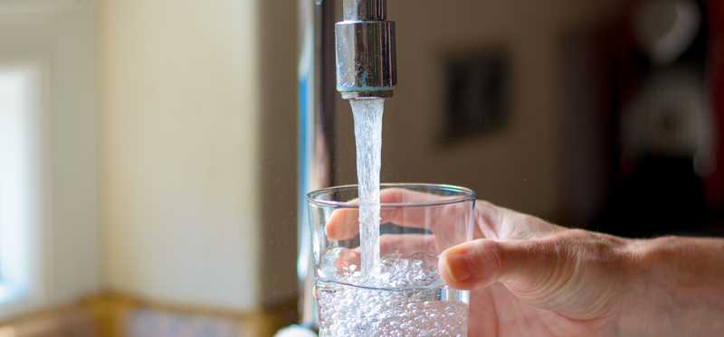 Water is poured into a glass from a tap.