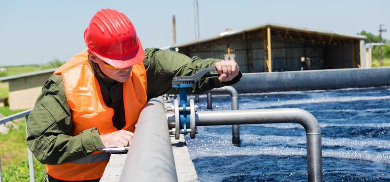 Person working on large water pipes.