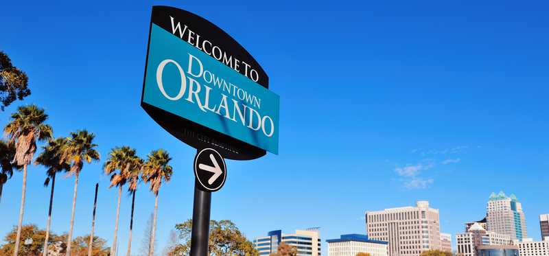 A "Welcome to Downtown Orlando" sign with downtown buildings in the background.