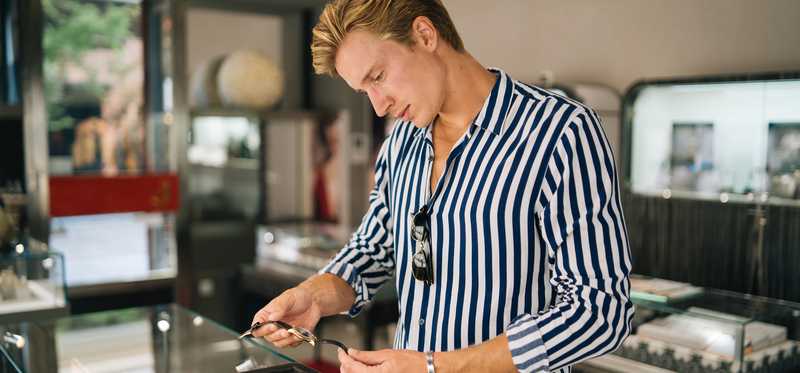 Well-dressed person looking at a watch in a shop.
