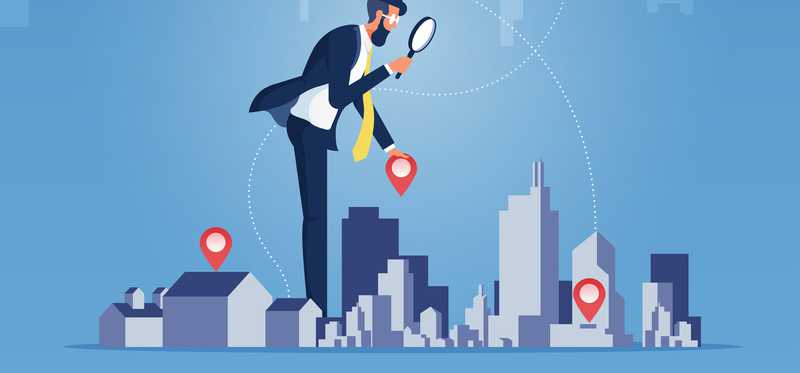 A person stands over a city with a magnifying glass.