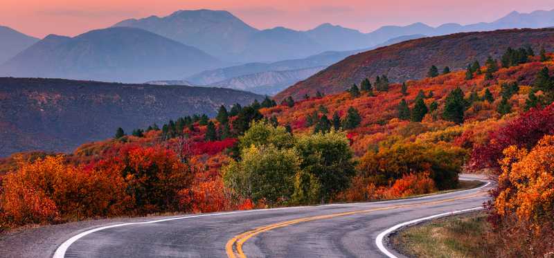 Winding road through foliage and mountains.