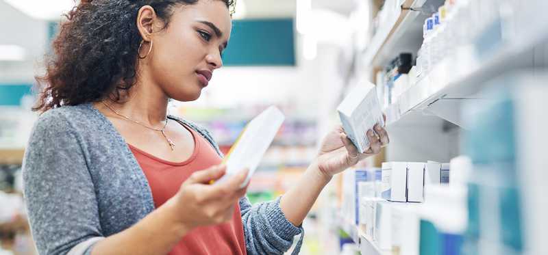 Person compares two over-the-counter medications in a drugstore.