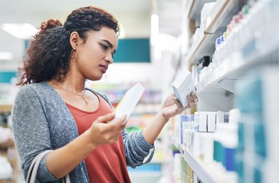 Person compares two over-the-counter medications in a drugstore.