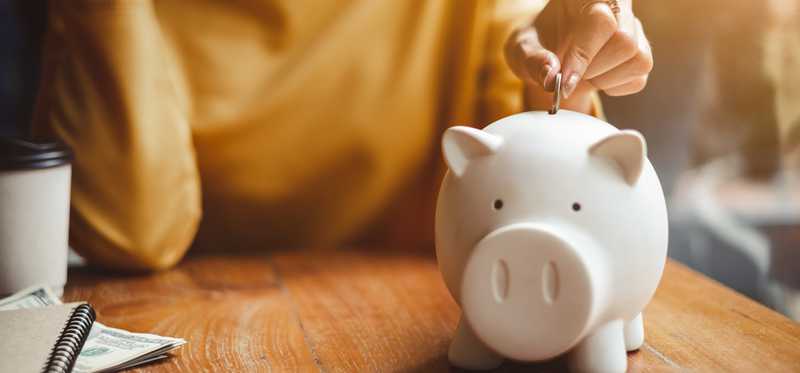 Woman inserting coin into piggy bank