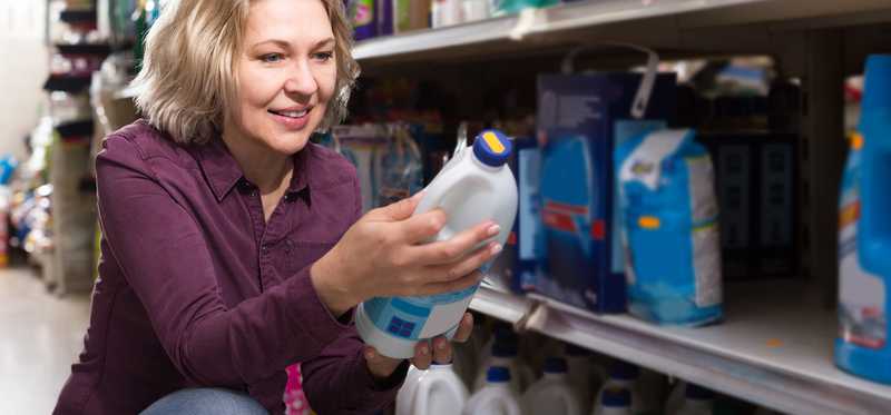 Woman shopping and holding bleach bottle