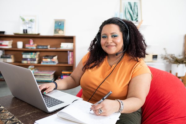 Person wearing headset while working on laptop and document.