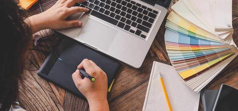 Woman at laptop with color swatches next to it.