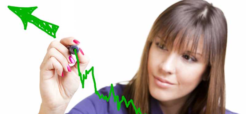 Woman drawing upward green line on transparent marker board