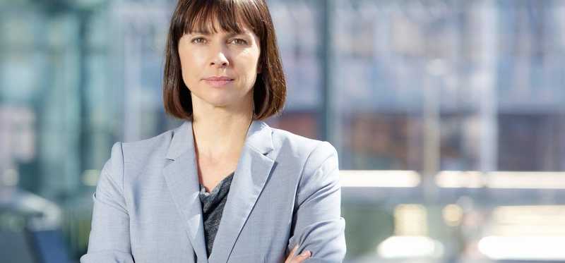Person in business suit with serious expression and crossed arms.