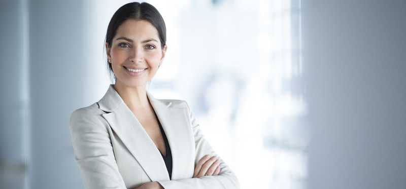 woman in business suit smiling with arms crossed