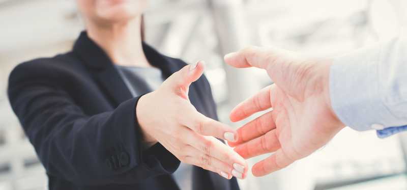 Person in suit extending a handshake.