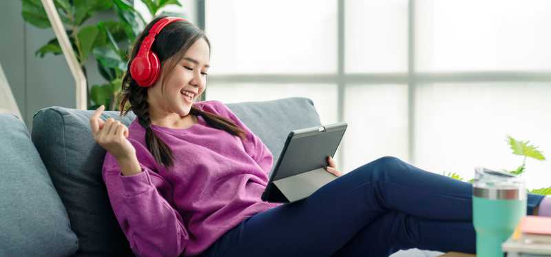 Person sitting on couch and listening to music on headphones.