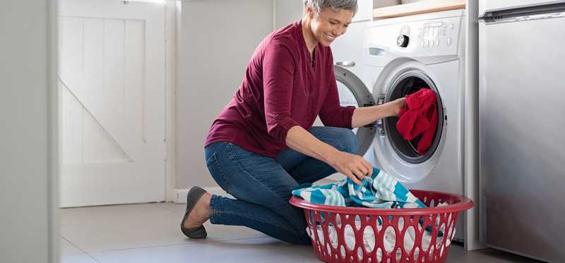A woman loading washing machine.