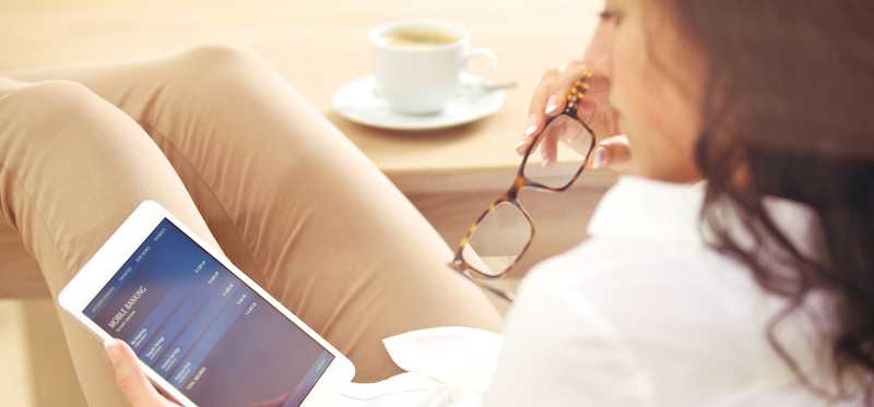 A woman sits in a chair and looks at her tablet.