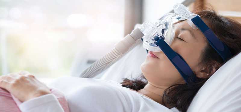 Woman lying down with a breathing mask on her face.